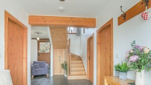 Ein Flur mit einer Holztreppe, einem Sofa, einem Tisch mit Pflanzen und einer Tür.