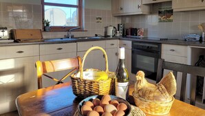 Una cocina con una mesa de madera, un bol de huevos, una botella de vino y una cesta.