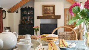 A cozy room with a dining table set for tea, a fireplace, and a wooden ceiling. - 3 bedroom accommodation in Llanbedrgoch, near Benllech (Llanbedrgoch, near Benllech)