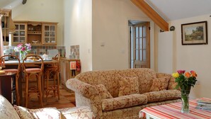 A cozy living room with a patterned sofa, a dining area with wooden chairs, and a kitchen with wooden cabinets. - 3 bedroom accommodation in Llanbedrgoch, near Benllech (Llanbedrgoch, near Benllech)