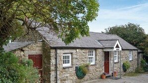 A stone cottage with a sloped roof, a wooden door, and a small window. - 3 bedroom accommodation in Llanbedrgoch, near Benllech (Llanbedrgoch, near Benllech)
