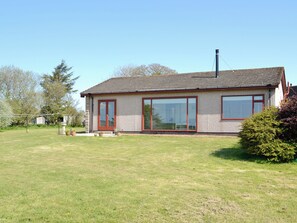 A single-story house with a sloped roof, a chimney, and a large window on the front.