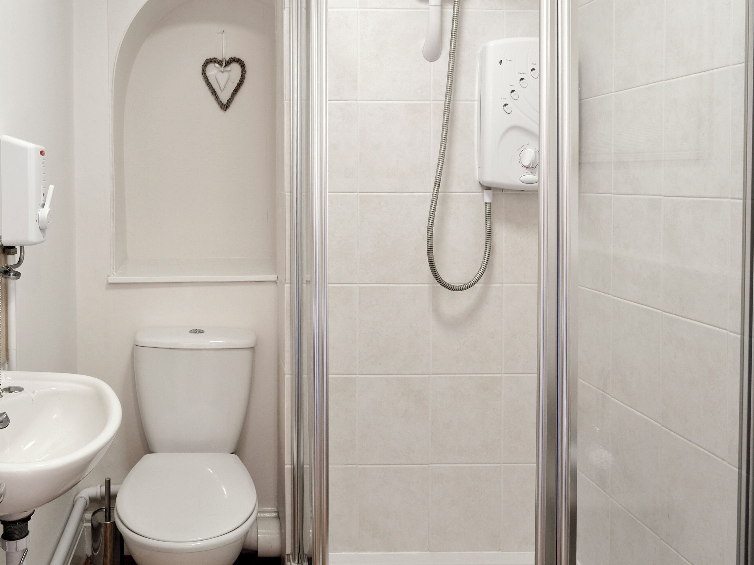 A bathroom with a toilet, a sink, and a shower enclosure.