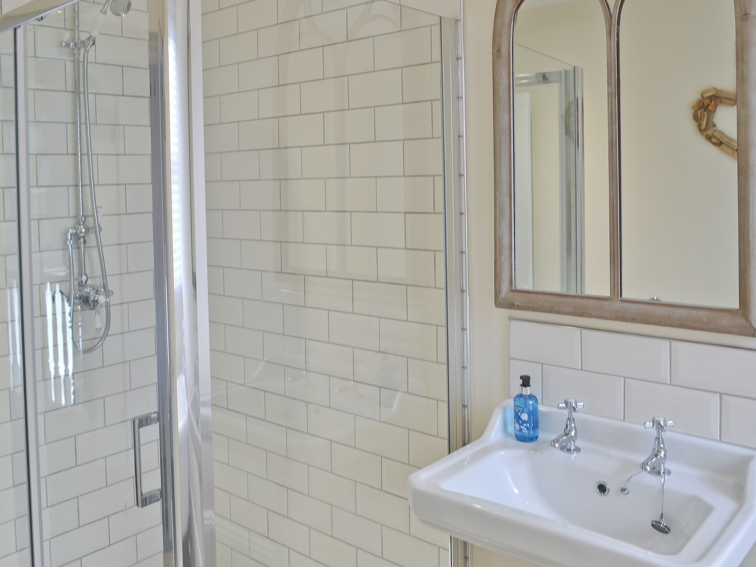 Un baño con ducha, lavamanos y espejo.
