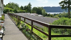 Une rangée de maisons mitoyennes avec une clôture en bois, un chemin et une vue sur un lac et des collines.