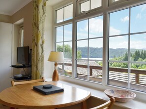 A room with a large window, a table with a lamp, a TV, and a chair. - 2 bedroom accommodation in Windermere (Windermere)