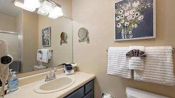 A bathroom with a sink, mirror, towel rack, and a painting of flowers.