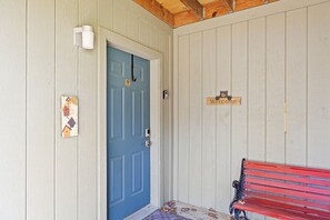 Una puerta azul con un cartel de 'Welcome', un banco y un accesorio de luz instalado en la pared.