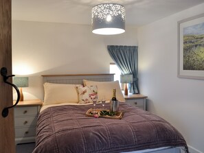 A bedroom with a bed, bedside tables, a lamp, a picture on the wall, and a window with curtains.