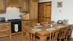 A kitchen with wooden cabinets, a stove, and a dining table set for six with placemats. - 3 bedroom accommodation in Brigham (Brigham)