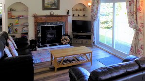 A living room with a fireplace, a television, a sofa, a coffee table, and a bookshelf. - 4 bedroom accommodation in Lochgoilhead, near Inverary (Lochgoilhead, near Inverary)