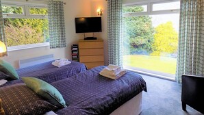A bedroom with two beds, a TV, a dresser, and a view of the outdoors. - 4 bedroom accommodation in Lochgoilhead, near Inverary (Lochgoilhead, near Inverary)