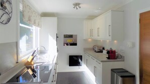A modern kitchen with white cabinets, a built-in oven, and a window providing natural light. - 4 bedroom accommodation in Lochgoilhead, near Inverary (Lochgoilhead, near Inverary)