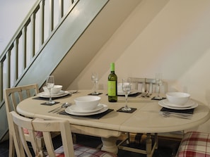 Une table à manger dressée avec de l’assiette blanche, des bols et des verres à vin, et une bouteille de vin blanc posée sur la table.