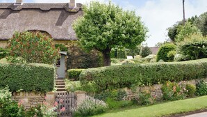 A traditional thatched-roof house with a stone wall and a wooden gate. - 2 bedroom accommodation in Westington, Chipping Campden (Westington, Chipping Campden)