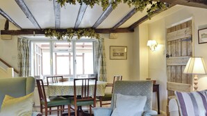 A cozy living room with a dining area, featuring wooden beams, a table with chairs, and a sofa. - 2 bedroom accommodation in Westington, Chipping Campden (Westington, Chipping Campden)