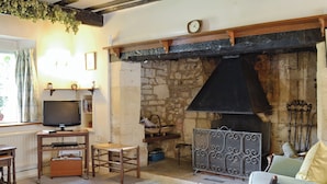 A cozy living room with a stone fireplace, a television, and a comfortable seating area. - 2 bedroom accommodation in Westington, Chipping Campden (Westington, Chipping Campden)