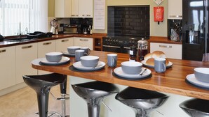 A modern kitchen with a central island, bar stools, a black stove, and a water dispenser. - 2 bedroom accommodation in Amble (Amble)