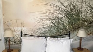 A bed with white bedding, two bedside tables with lamps, and a large plant in the background. - 2 bedroom accommodation in Amble (Amble)