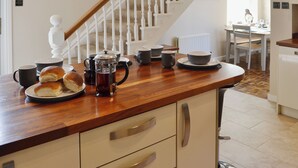 A kitchen with a wooden countertop, a coffee pot, cups, and a dining table with chairs. - 2 bedroom accommodation in Amble (Amble)