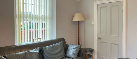 A modern living room with a leather sofa, a standing lamp, and a door.