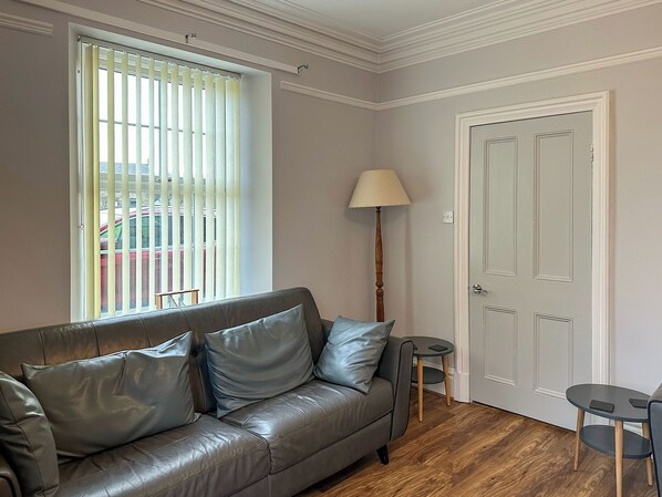 Un salon moderne avec un canapé en cuir, un lampadaire et une porte.