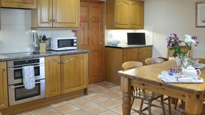 A kitchen with wooden cabinets, a microwave, a stove, and a dining table with chairs.