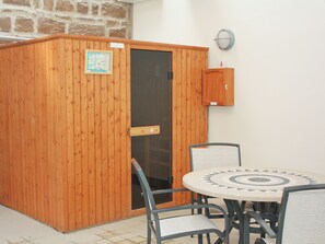 A wooden cabinet with a glass door, a small wooden cabinet above it, and a round table with chairs. - A detached cottage only five miles from the impressive Bamburgh Castle. (Bamburgh)