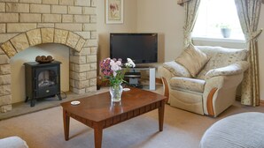 A living room with a brick fireplace, a television, a sofa, and a coffee table.