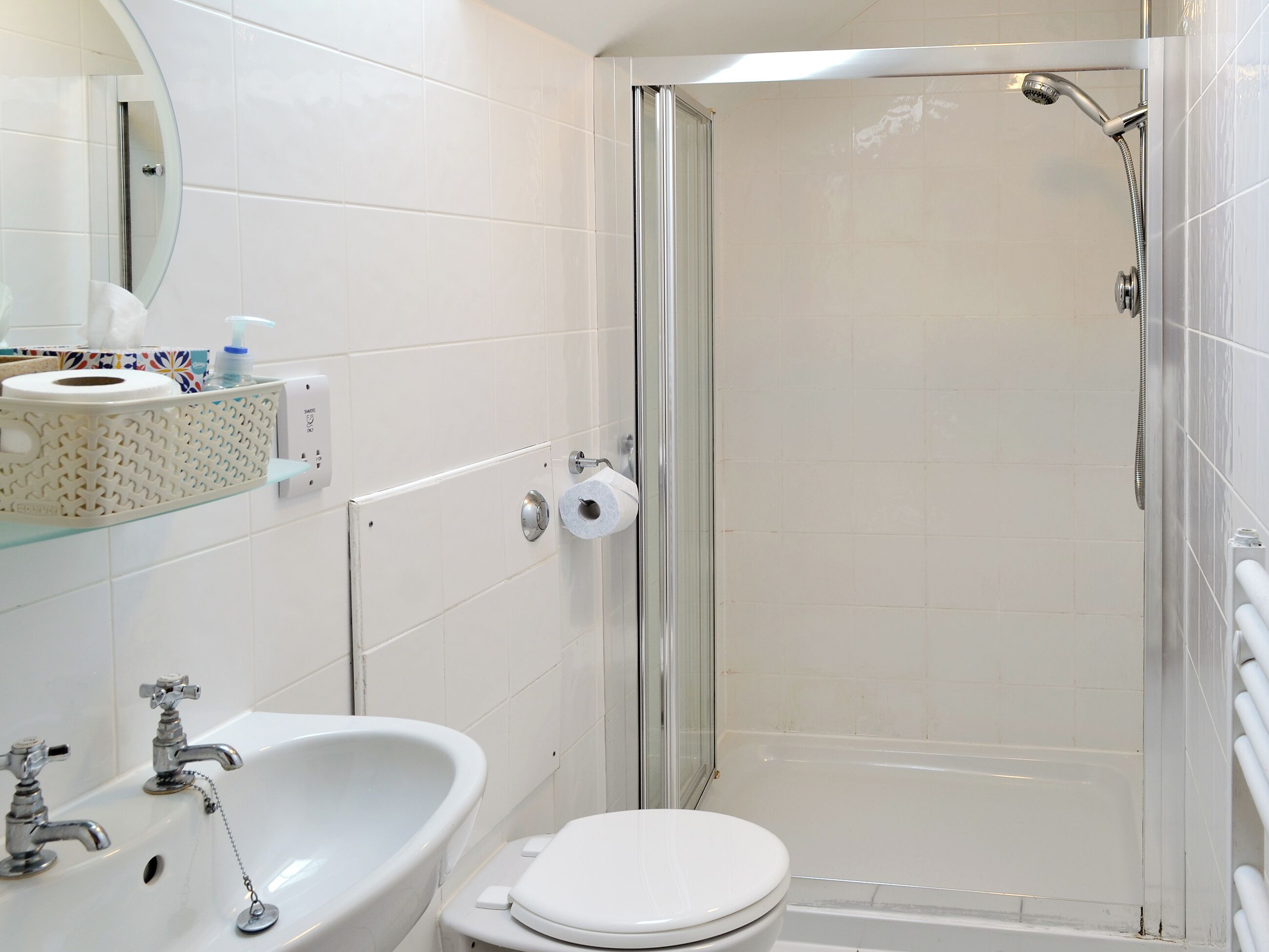 A bathroom with a shower, toilet, sink, and a mirror.