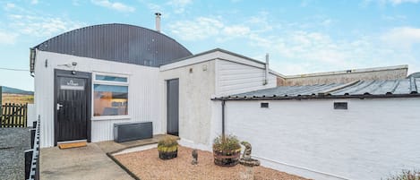 A building with a black door, a window, and a white exterior wall.