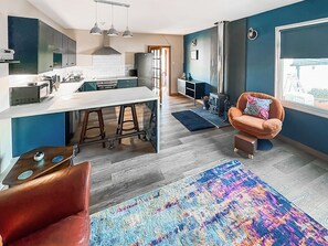 A modern kitchen with a central island, bar stools, and a dining table.