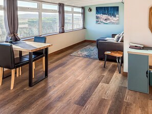 A room with a dining table, a sofa, a small cabinet, and a painting on the wall. - 1 bedroom accommodation in Bargrennan, near Glentrool (Bargrennan, near Glentrool)