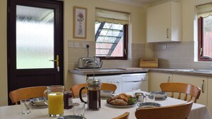 Een keuken met een ontbijttafel, compleet met een karaf sinaasappelsap en een bord gebak.