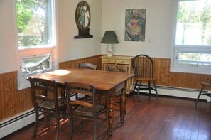 Une salle à manger avec une table et des chaises en bois, une lampe, un miroir et un tableau accroché au mur.