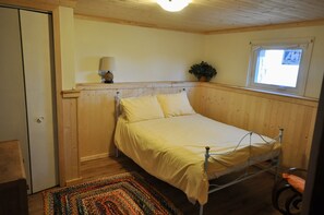 Une petite chambre avec un lit simple, des murs en bois et une fenêtre.