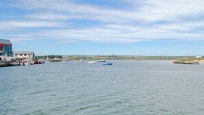 A harbor with boats, a building with a red roof, and a distant view of a town. - 3 bedroom accommodation in Amble (Amble)