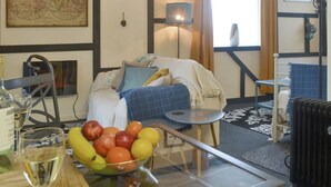Et værelse med en seng, et bord med frugt og et vinglas, et kort på væggen og en lampe.