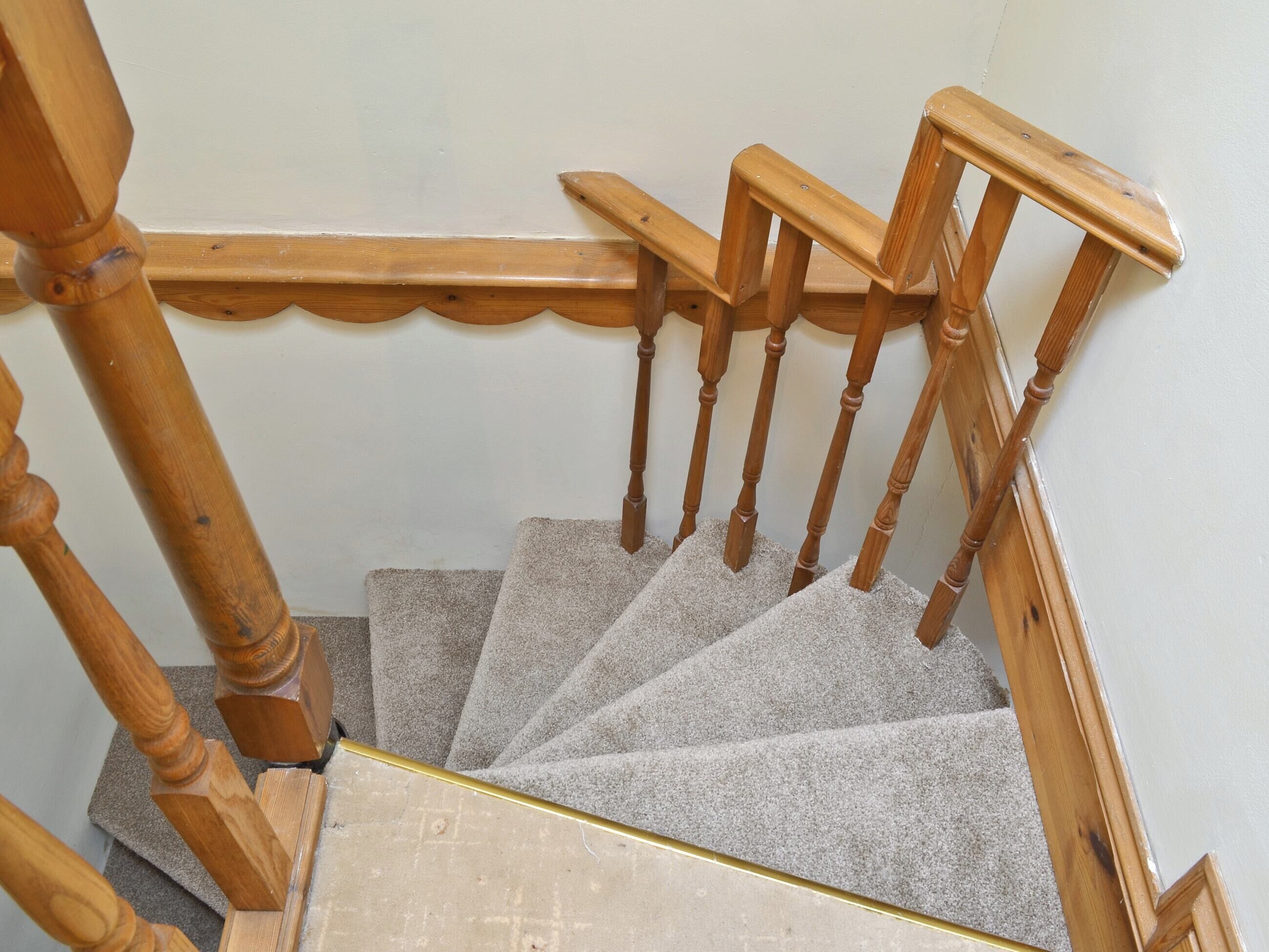 A wooden staircase with a handrail and carpeted steps.