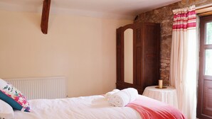 Une chambre à coucher avec un lit, une armoire en bois, une petite table avec une lampe et une fenêtre avec des rideaux.