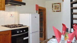 Une cuisine équipée d’une cuisinière, d’un four et d’un réfrigérateur. Il y a un meuble en bois au-dessus de la cuisinière et une fenêtre avec une porte.