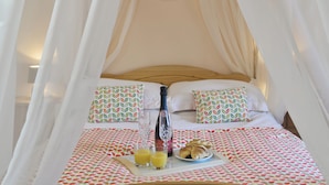 A bed with a canopy, two patterned pillows, a bedside table with a bottle, glasses, and a plate of croissants and juice. - 1 bedroom accommodation in Glynarthen, near Cardigan (Glynarthen, near Cardigan)