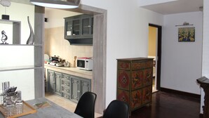 Una cocina moderna con armarios oscuros, un microondas y una zona de comedor con una mesa y sillas de madera.