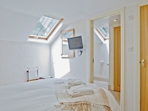 A bedroom with a bed, a TV, a skylight, a door, and a wall socket. - 4 bedroom accommodation in Mount, near Bodmin (Mount, near Bodmin)