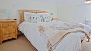 A bedroom with a wooden bed frame, white bedding, two bedside tables with lamps, and a skylight. - 4 bedroom accommodation in Mount, near Bodmin (Mount, near Bodmin)