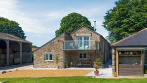 A stone house with a balcony, a garage, and a lawn. - 4 bedroom accommodation in Mount, near Bodmin (Mount, near Bodmin)