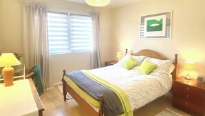 A neatly arranged bedroom with a bed, bedside tables, a desk, and a chair. - 2 bedroom accommodation in Beadnell (Beadnell)