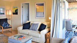 A cozy living room with a sofa, armchair, ottoman, and a small table with books. - 2 bedroom accommodation in Beadnell (Beadnell)