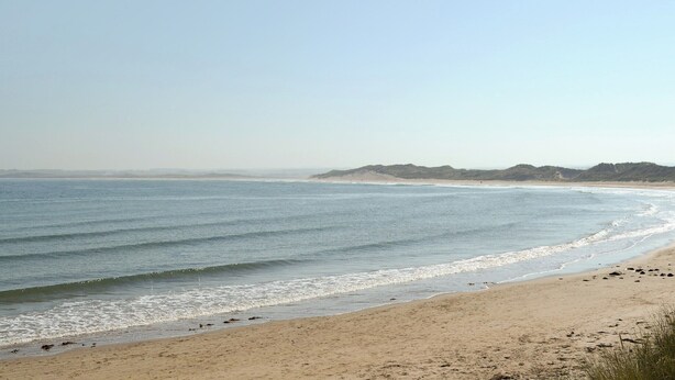 A beach with clear skies, gentle waves, and distant hills. - 2 bedroom accommodation in Beadnell (Beadnell)