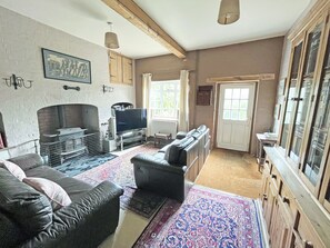 A living room with a fireplace, a sofa, a television, and a patterned rug.